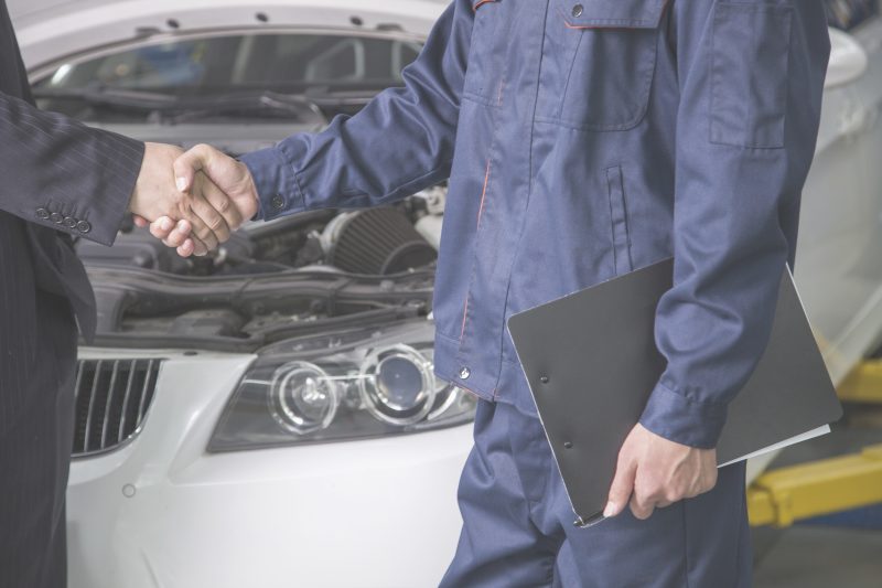 A auto mechanic shaking hands with a client.