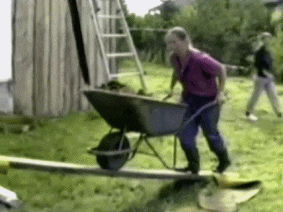 Man pushing wheel barrel and falls off 2x4 into wheel barrel