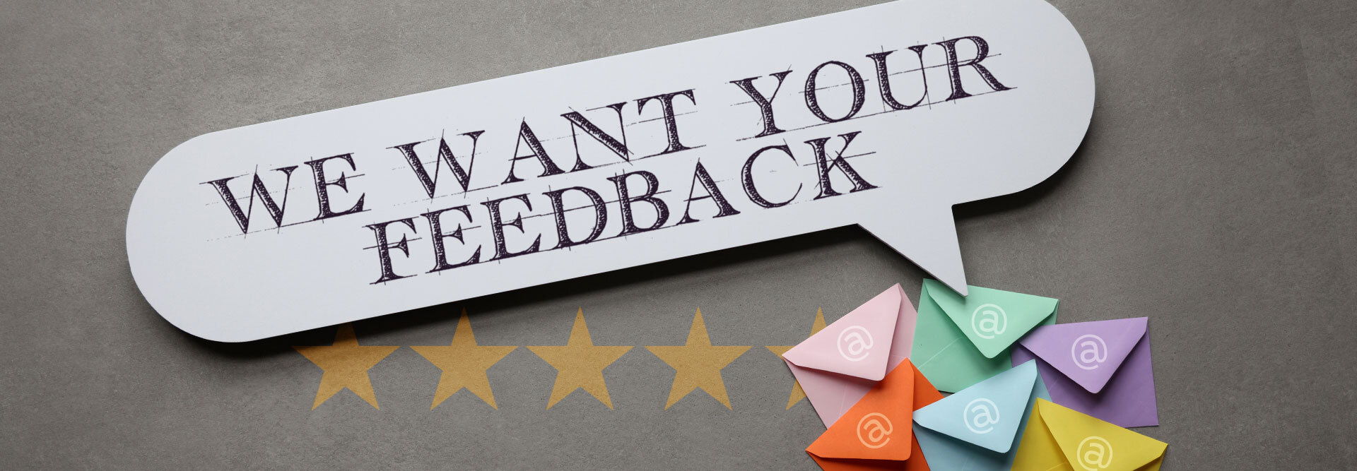 The words “We want your feedback” are written on a speech bubble with little colored envelopes and a 5-star review in the picture to depict review request email examples.
