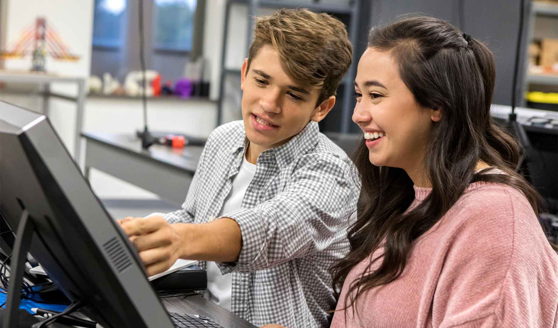Vendasta tech camp with two kids working on a computer and smiling<br />
